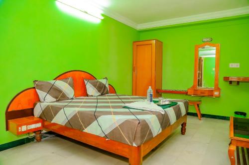 a green bedroom with a bed and a mirror at Park Palace Inn in Erode