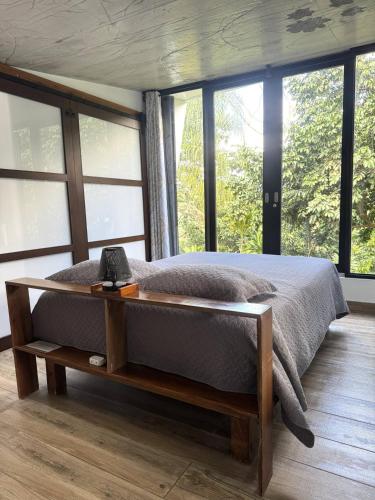 a bedroom with a bed with a table and windows at Farm Suite Bienteveo in Naranjito