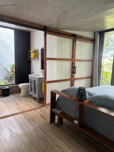 a bedroom with a bed and a bathroom with windows at Farm Suite San Pedrito in Naranjito