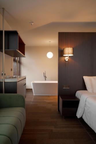 a bathroom with a bed and a bath tub and a couch at Len Hotel in Da Lat