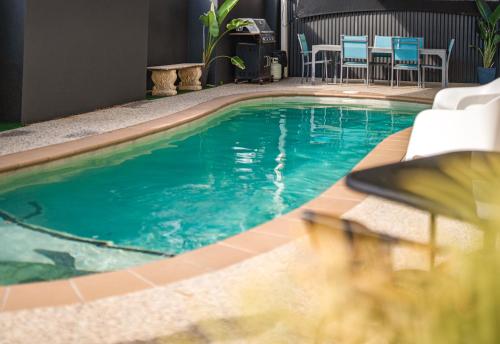 a swimming pool in a hotel with chairs and tables at Caboolture Gateway Motel in Caboolture
