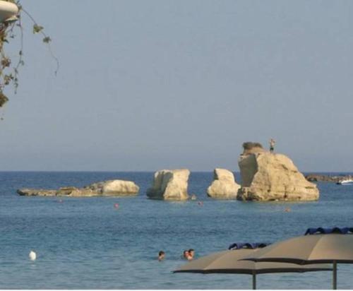 people swimming in the water near rocks in the ocean at Casa Roby 120 mt Beach in Fontane Bianche