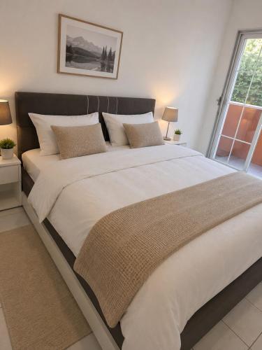 a large bed with white sheets and pillows in a bedroom at Mediterrane Ferienwohnung mit Whirlpool und Weitblick in Merchweiler