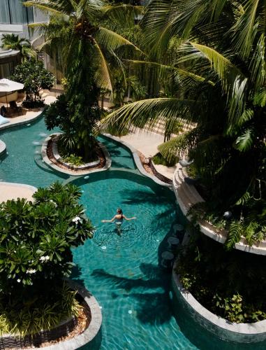 a person swimming in a pool with palm trees at Hotel Vellita Siem reap in Siem Reap
