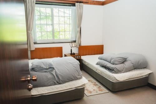 two twin beds in a room with a window at ラリックス蓼科 in Chino
