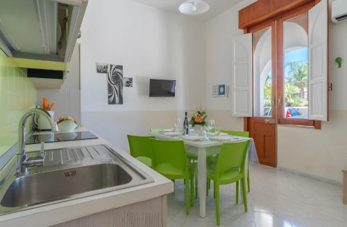 a kitchen with a sink and a table with green chairs at Villa Anny con idromassaggio in Avola