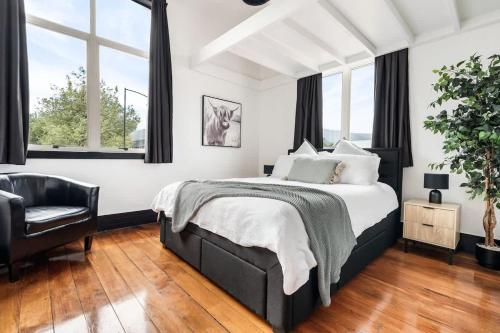 a bedroom with a bed and a chair at The Nelson Loft - Sauna, Balcony & City Centre Living in Nelson