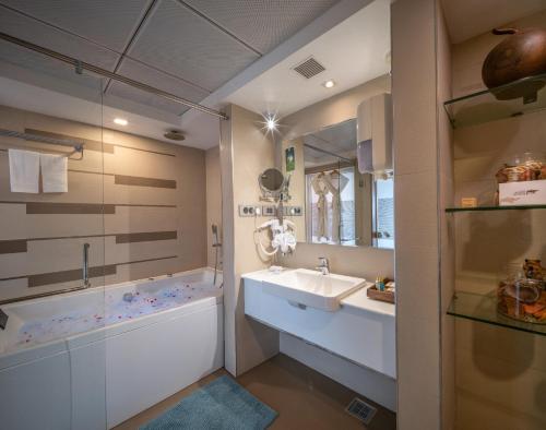 a bathroom with a sink and a tub and a mirror at Chandys Windy Woods Munnar in Munnar
