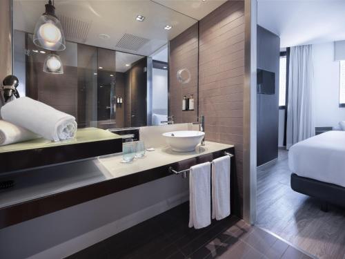a bathroom with a sink and a large mirror at Hotel Barcelona Condal Mar, Affiliated by Meliá in Barcelona