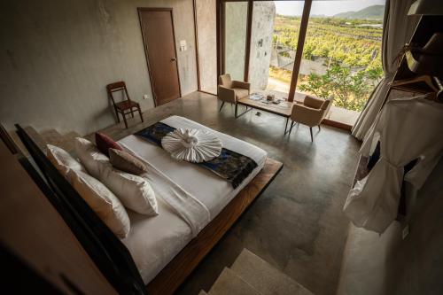 a bedroom with a bed with pillows and a large window at La Plantation Villa in Kampot
