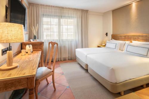 a bedroom with a large white bed and a desk at Meliá Sol y Nieve in Sierra Nevada