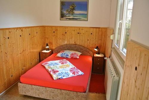 a bedroom with a red bed with two pillows on it at Apartmaji NIKA in Izola