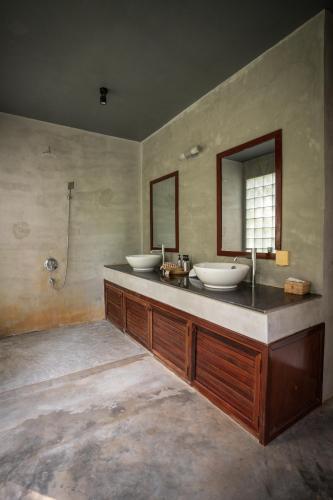 a bathroom with two sinks and two mirrors at La Plantation Villa in Kampot