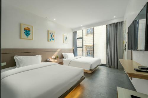 a hotel room with two beds and a window at 贵客心宿 Xiamen Guike Xinsu in Xiamen