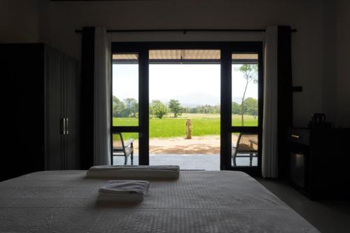 ein Schlafzimmer mit einem Bett und einer Glasschiebetür in der Unterkunft Ward 58 in Wellawaya