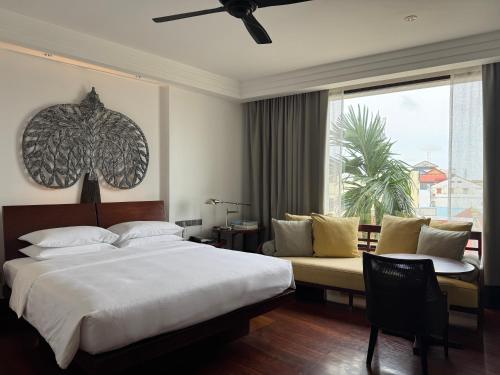 a bedroom with a bed and a couch and a window at Park Hyatt Siem Reap in Siem Reap