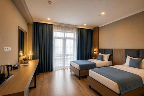 a hotel room with two beds and a desk at Sara Hotel Bishkek in Bishkek