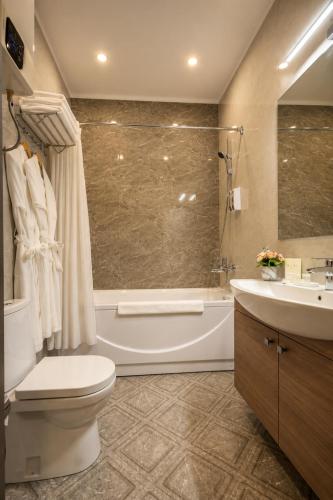 a bathroom with a tub and a toilet and a sink at Sara Hotel Bishkek in Bishkek