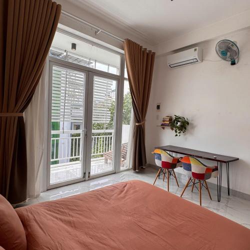 a bedroom with a bed and a desk and a window at Nhà của Buôn in Buon Ma Thuot