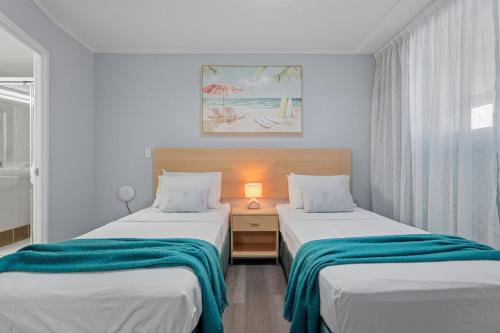a bedroom with two beds and a lamp on a table at Moana Condo | Close to Beach in Caloundra