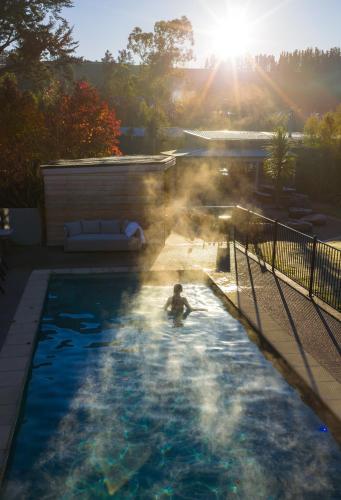 a man in a swimming pool with the sun shining at Manawa Retreat in Whitecliffs