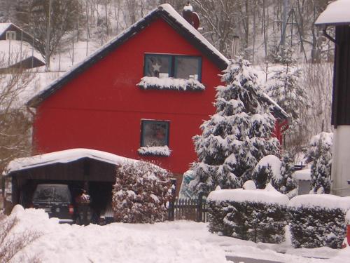 a red barn with a snow covered christmas tree at Ferienwohnung An der Innerste in Wildemann