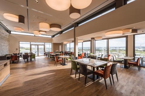 a restaurant with tables and chairs and large windows at Hotel TheGreen in Cologne