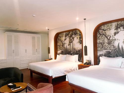 a hotel room with two beds and a chair at Koulen Central Premier Suites in Siem Reap