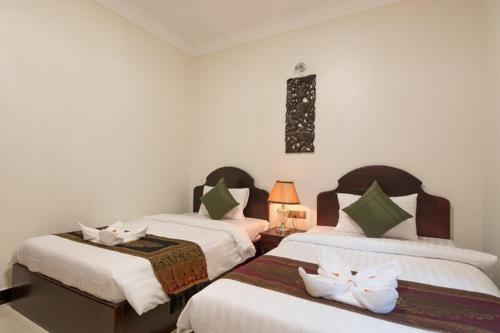 a bedroom with two beds with white sheets at Raksmey Angkor Boutique in Siem Reap