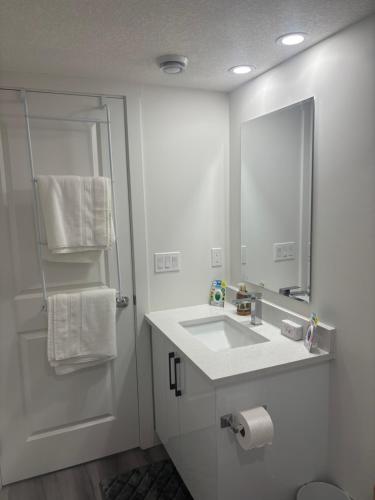 a white bathroom with a sink and a mirror at Peniel Place in Airdrie