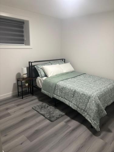 a bedroom with a bed with a green comforter at Peniel Place in Airdrie