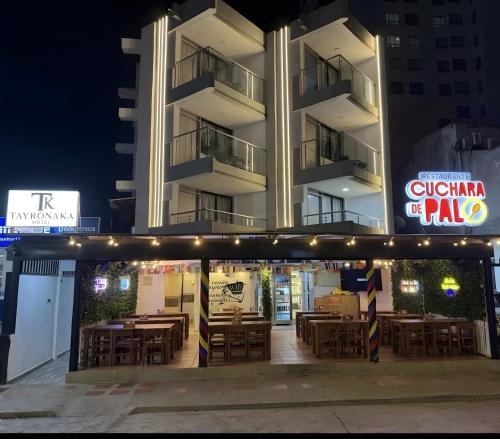 a restaurant with wooden tables in front of a building at Hotel Tayronaka in Santa Marta