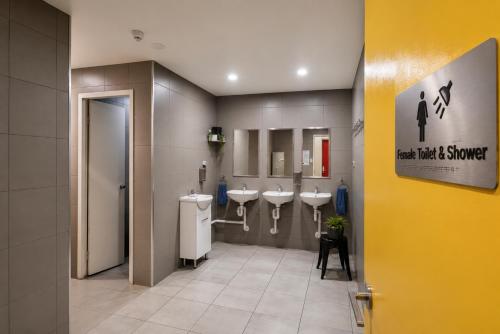 a bathroom with three sinks and three urinals at Perth City Backpackers Hostel - note - Valid passport required to check in in Perth