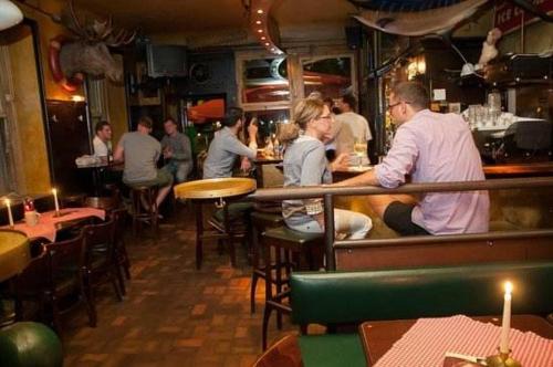 a group of people sitting at a bar in a restaurant at Hemingway`s Heidelberg Hostel in Heidelberg