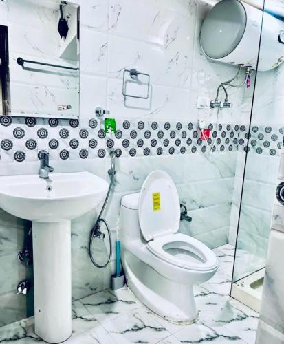 a white bathroom with a toilet and a sink at MGallery in Srinagar