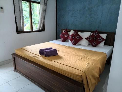 a bedroom with a bed with red and white pillows at Wild View Stay in Habarana