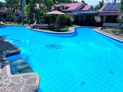 a blue swimming pool with a table and a house at Villa Formosa Panglao in Panglao Island