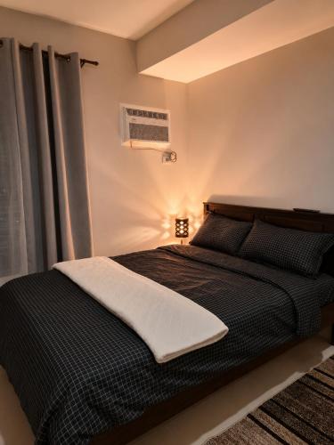 a bedroom with a black bed with a window at Jtower residences mandaue 27flr in Mandaue City