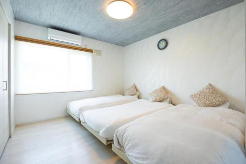 two beds in a bedroom with a clock on the wall at furano ski rabi in Furano