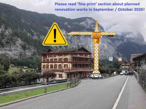 a yellow sign on the side of a road with a building at Hotel Staubbach in Lauterbrunnen
