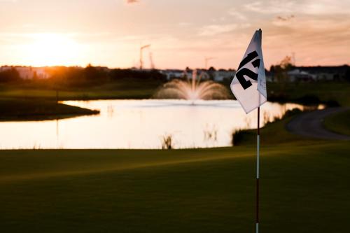 a flag on a golf course with a lake at Hotel TheGreen in Cologne