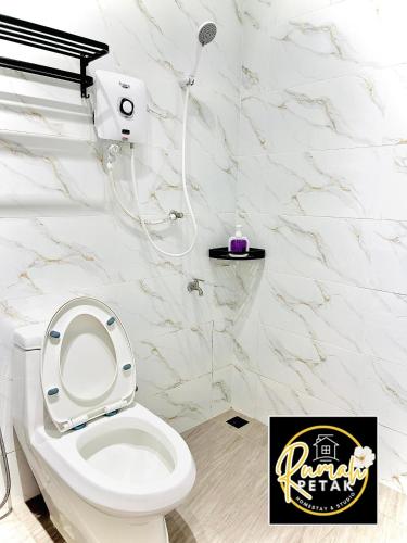 a white bathroom with a toilet and a shower at Rumah Petak Melor Muji Concept in Melur
