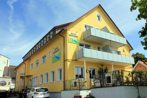 a yellow building with cars parked in front of it at Hotel Seehalde in Nonnenhorn