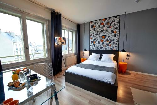 a bedroom with a bed and a table and windows at L'aparthoteL LhL in Dijon