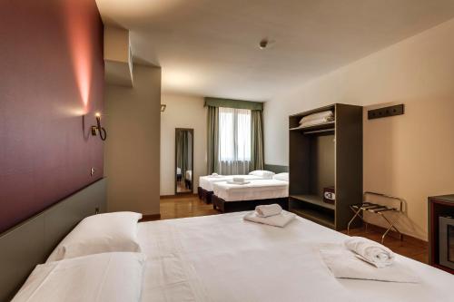 ein Hotelzimmer mit zwei Betten und einem Spiegel in der Unterkunft HC Hotel Cremona Pilgrim's in Cicognolo