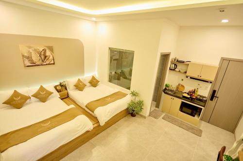 a bedroom with two beds and a small kitchen at Maison Boutique Hotel - Bình An in Phước Lộc Xã