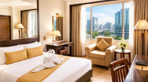 a hotel room with a bed and a chair and a window at Arnoma Hotel Bangkok in Bangkok