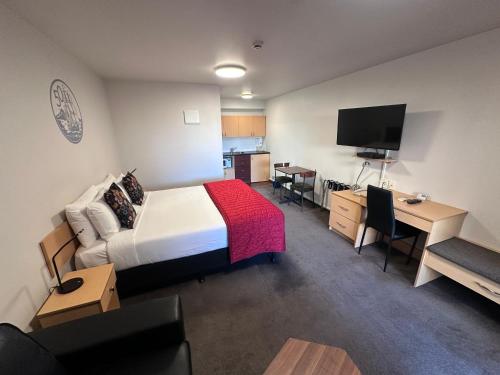 a hotel room with a bed and a desk and a television at ASURE Centrepoint Motel in Christchurch