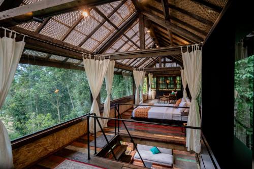 a bedroom in a tree house with a balcony at Kalpa House Sidemen in Sidemen