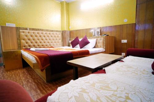 a hotel room with two beds and a table at Hotel King Palace in Shimla